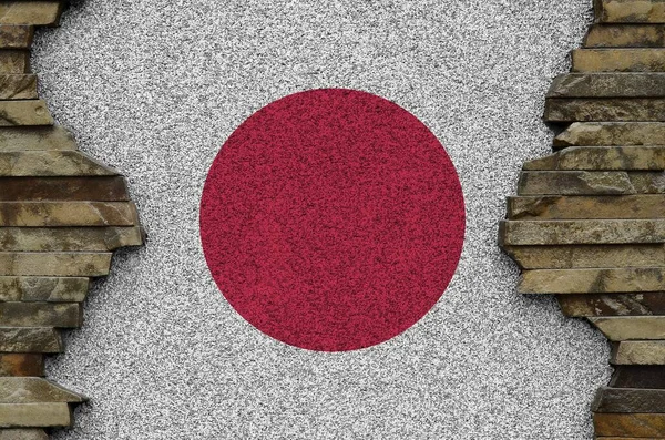 Japan flag depicted in paint colors on old stone wall close up. Textured banner on rock wall background