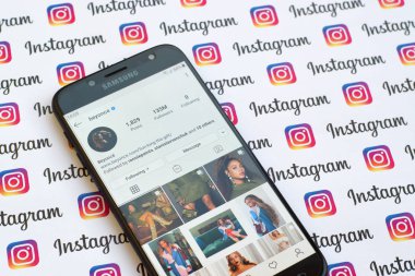 Kağıt instagram pankartıyla akıllı telefon ekranında Beyonce resmi instagram hesabı.