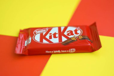 Kırmızı ambalajlı Kit Kat çikolataları sarı ve kırmızı arka planda yatar. Kit Kat, Birleşik Krallık 'ta Rowntree' s of York tarafından yaratıldı ve şimdi küresel olarak Nestle tarafından üretiliyor.