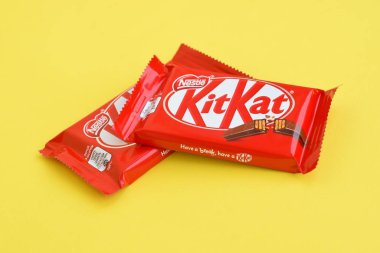 Kırmızı ambalajlı Kit Kat çikolatası sarı arka planda yatıyor. Kit Kat, Birleşik Krallık 'ta Rowntree' s of York tarafından yaratıldı ve şimdi küresel olarak Nestle tarafından üretiliyor.