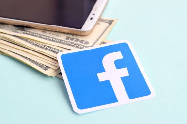 Facebook kağıt logosu dolar ve akıllı telefon dolu.