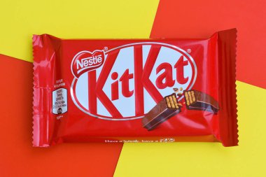 Kırmızı ambalajlı Kit Kat çikolataları sarı ve kırmızı arka planda yatar. Kit Kat, Birleşik Krallık 'ta Rowntree' s of York tarafından yaratıldı ve şimdi küresel olarak Nestle tarafından üretiliyor.