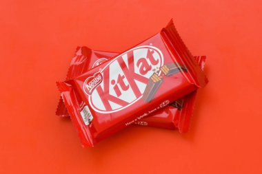 Kırmızı ambalajlı Kit Kat çikolatası kırmızı arka planda yatıyor. Kit Kat, Birleşik Krallık 'ta Rowntree' s of York tarafından yaratıldı ve şimdi küresel olarak Nestle tarafından üretiliyor.