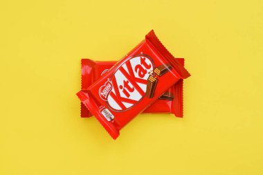 Kırmızı ambalajlı Kit Kat çikolatası sarı arka planda yatıyor. Kit Kat, Birleşik Krallık 'ta Rowntree' s of York tarafından yaratıldı ve şimdi küresel olarak Nestle tarafından üretiliyor.