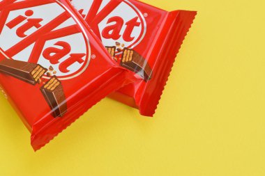 Kırmızı ambalajlı Kit Kat çikolatası sarı arka planda yatıyor. Kit Kat, Birleşik Krallık 'ta Rowntree' s of York tarafından yaratıldı ve şimdi küresel olarak Nestle tarafından üretiliyor.