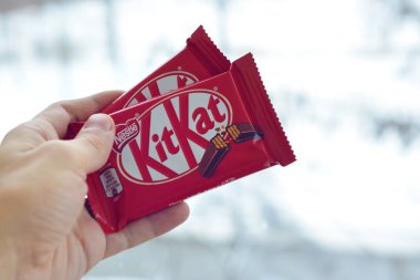 Kit Kat çikolatası, erkek eli karlı arka planda. Kit Kat, Birleşik Krallık 'ta Rowntree' s of York tarafından yaratıldı ve şimdi küresel olarak Nestle tarafından üretiliyor.
