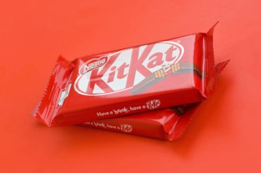 Kırmızı ambalajlı Kit Kat çikolatası kırmızı arka planda yatıyor. Kit Kat, Birleşik Krallık 'ta Rowntree' s of York tarafından yaratıldı ve şimdi küresel olarak Nestle tarafından üretiliyor.