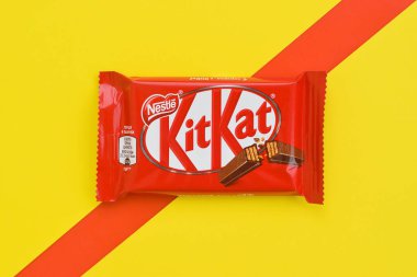 Kırmızı ambalajlı Kit Kat çikolataları sarı ve kırmızı arka planda yatar. Kit Kat, Birleşik Krallık 'ta Rowntree' s of York tarafından yaratıldı ve şimdi küresel olarak Nestle tarafından üretiliyor.