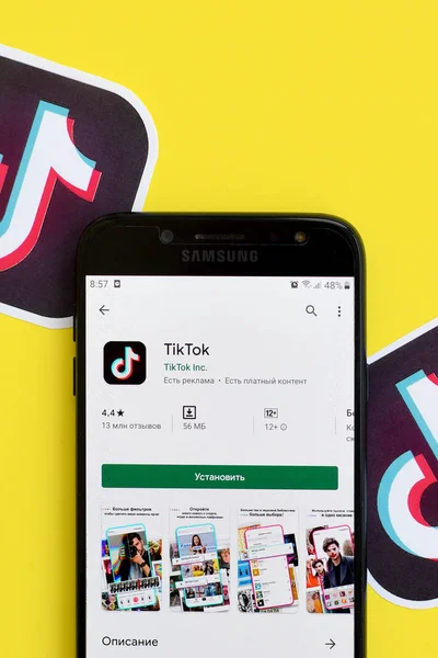 Aplicación Tiktok en playmarket en pantalla Samsung smartphone sobre fondo amarillo. TikTok es un popular servicio de redes sociales para compartir videos propiedad de ByteDance — Foto de Stock