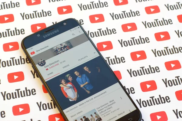 One Direction official youtube channel on smartphone screen on paper youtube background. — Stock Photo, Image