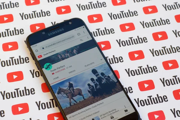 Dude Perfect official youtube channel on smartphone screen on paper youtube background. — Stock Photo, Image