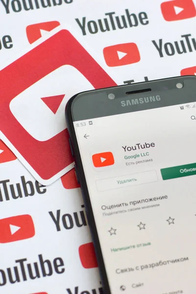 Youtube app op samsung smartphone scherm op papier banner met kleine youtube logo 's en inscripties. Youtube is een dochteronderneming van Google en het populairste Amerikaanse videoplatform — Stockfoto