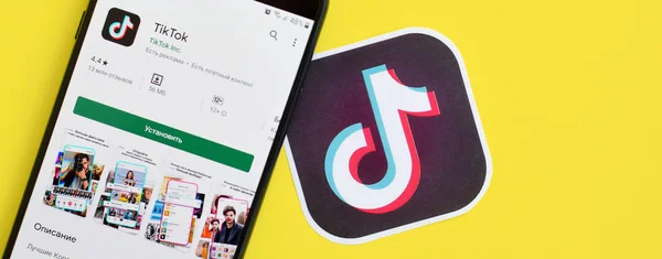 Aplikasi Tiktok di playmarket pada layar telepon pintar samsung pada latar belakang kuning. TikTok adalah layanan jejaring sosial berbagi video populer yang dimiliki oleh ByteDance — Stok Foto