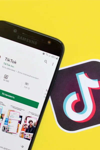 Aplicación Tiktok en playmarket en pantalla Samsung smartphone sobre fondo amarillo. TikTok es un popular servicio de redes sociales para compartir videos propiedad de ByteDance —  Fotos de Stock