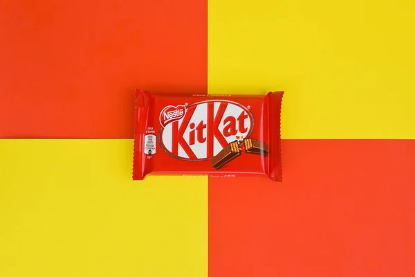 红色包装的Kit Kat巧克力棒躺在黄色和红色的背景上。 Kit kat由英国York的Rowntree's创作，目前由Nestle在全球发行 — 图库照片