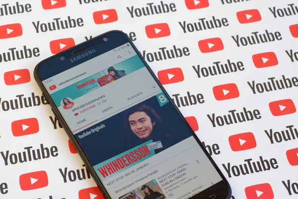 Whinderssonnunes official youtube channel on smartphone screen on paper youtube background. — Stock Photo, Image