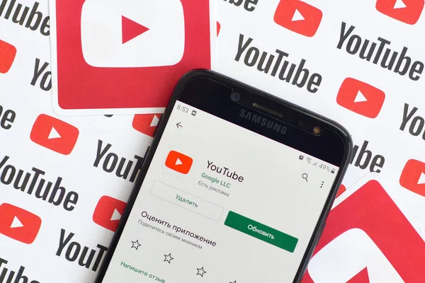 Youtube app on samsung smartphone screen on paper banner with small youtube logos and inscriptions. YouTube is Google subsidiary and American most popular video-sharing platform — Stock Photo, Image