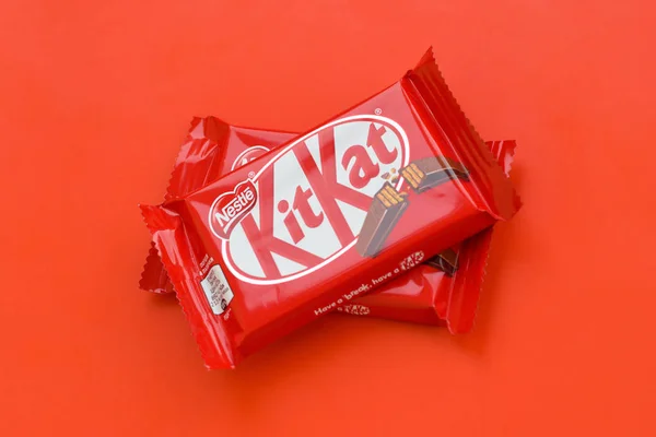红色包装的Kit Kat巧克力棒躺在红色背景上。 Kit kat由英国York的Rowntree's创作，目前由Nestle在全球发行 — 图库照片
