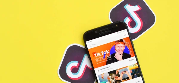 Applicazione Tiktok sullo schermo dello smartphone samsung su sfondo giallo. TikTok è un popolare servizio di social networking di condivisione video di proprietà di ByteDance — Foto Stock