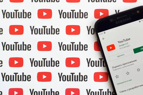 Youtube app on samsung smartphone screen on paper banner with small youtube logos and inscriptions. YouTube is Google subsidiary and American most popular video-sharing platform — Stock Photo, Image