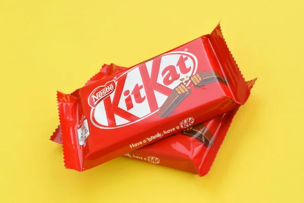 Kit Kat barre de chocolat dans un emballage rouge repose sur fond jaune. Kit kat créé par Rowntree de York au Royaume-Uni et est maintenant produit dans le monde entier par Nestlé — Photo