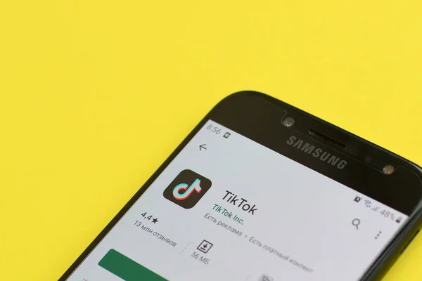 Aplikasi Tiktok di playmarket pada layar telepon pintar samsung pada latar belakang kuning. TikTok adalah layanan jejaring sosial berbagi video populer yang dimiliki oleh ByteDance — Stok Foto