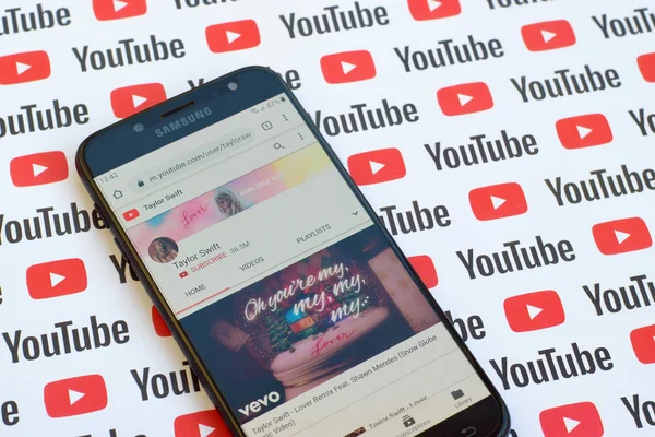 Taylor Swift official youtube channel on smartphone screen on paper youtube background. — Stock Photo, Image