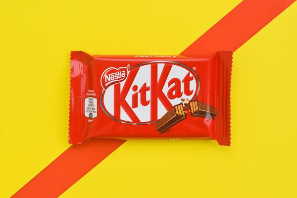 红色包装的Kit Kat巧克力棒躺在黄色和红色的背景上。 Kit kat由英国York的Rowntree's创作，目前由Nestle在全球发行 — 图库照片