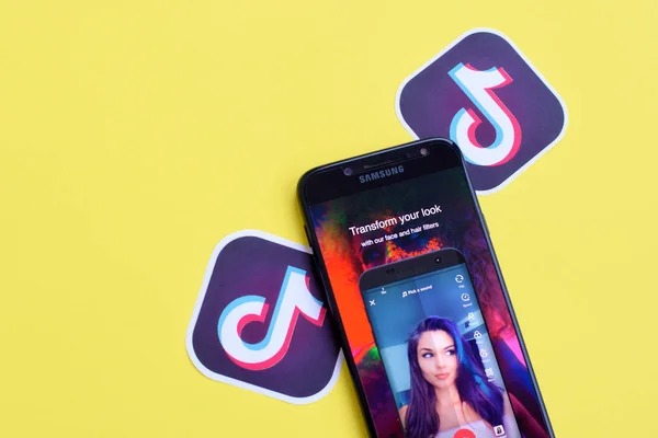 Aplicación Tiktok en pantalla Samsung smartphone sobre fondo amarillo. TikTok es un popular servicio de redes sociales para compartir videos propiedad de ByteDance —  Fotos de Stock