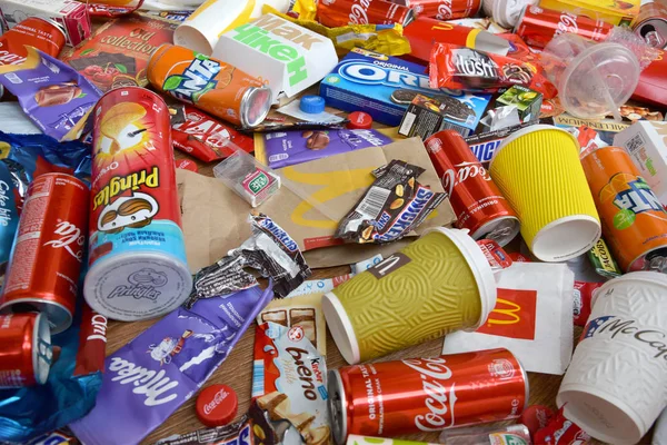 Grote stapel van vele wegwerp gekleurde afval van eetbare producten van beroemde voedsel-en drankenfabrikanten. Natronblikjes en chocoladerepen in een stapel — Stockfoto