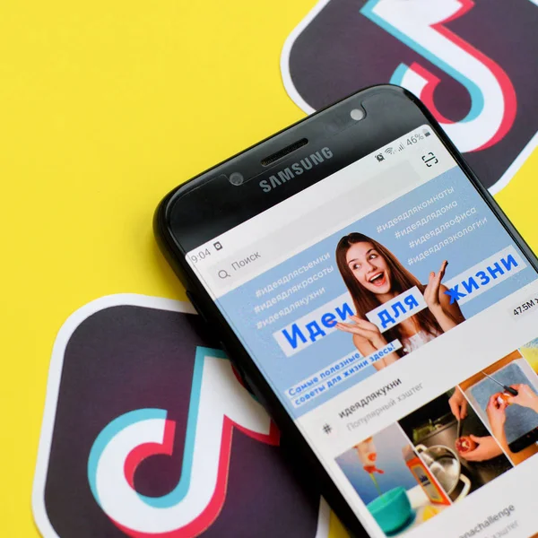 Aplicación Tiktok en pantalla Samsung smartphone sobre fondo amarillo. TikTok es un popular servicio de redes sociales para compartir videos propiedad de ByteDance — Foto de Stock