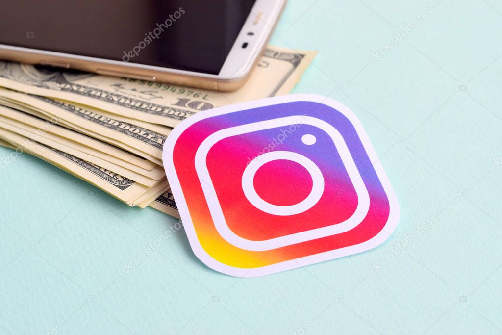 NY, USA - DECEMBER 26, 2019: Instagram paper logo lies with envelope full of dollar bills and smartphone