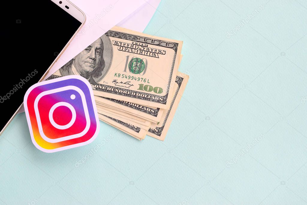 NY, USA - DECEMBER 26, 2019: Instagram paper logo lies with envelope full of dollar bills and smartphone