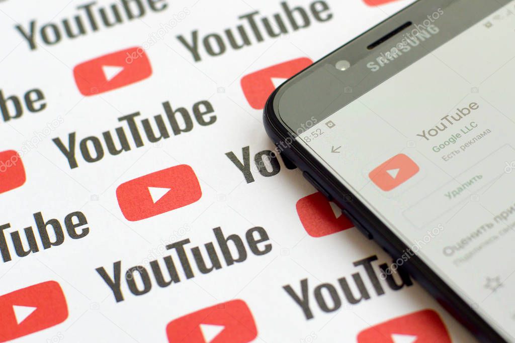 NY, USA - DECEMBER 5, 2019: Youtube app on samsung smartphone screen on paper banner with small youtube logos. YouTube is Google subsidiary and American most popular video-sharing platform
