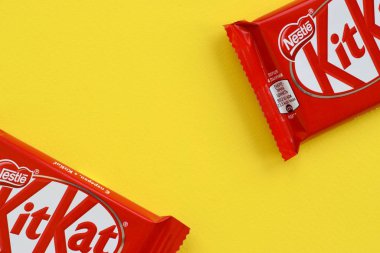 Kırmızı ambalajlı Kit Kat çikolatası sarı arka planda yatıyor. Kit Kat, Birleşik Krallık 'ta Rowntree' s of York tarafından yaratıldı ve şimdi küresel olarak Nestle tarafından üretiliyor.