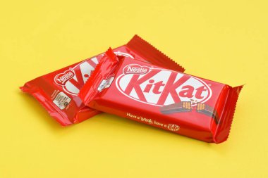 Kırmızı ambalajlı Kit Kat çikolatası sarı arka planda yatıyor. Kit Kat, Birleşik Krallık 'ta Rowntree' s of York tarafından yaratıldı ve şimdi küresel olarak Nestle tarafından üretiliyor.