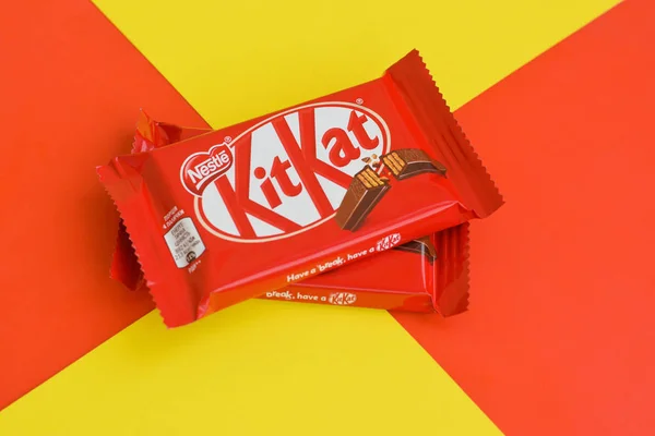 Kit Kat csokoládé rúd piros csomagolásban fekszik sárga és piros háttérrel. Kit kat által létrehozott Rowntree of York az Egyesült Királyságban, és most világszerte termelt Nestle — Stock Fotó