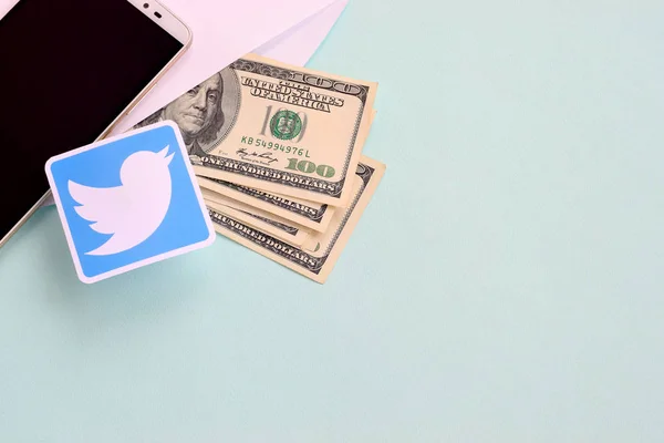 Twitter-Papier-Logo liegt mit Umschlag voller Dollarscheine und Smartphone — Stockfoto