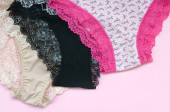 weiße, schwarze und rosa Damenunterwäsche mit Spitze auf rosa Hintergrund mit Kopierraum. Werbung für ein Geschäft mit schöner und bequemer Damenunterwäsche