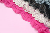 weiße, schwarze und rosa Damenunterwäsche mit Spitze auf rosa Hintergrund mit Kopierraum. Werbung für ein Geschäft mit schöner und bequemer Damenunterwäsche