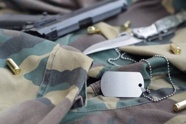 9 mm 'lik kurşunlar ve tabancayla ordu künyesi katlanmış yeşil kumaş üzerinde duruyor.