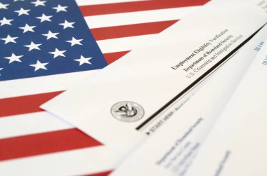 I-9 Employment Eligibility Verification blank form lies on United States flag with envelope from Department of Homeland Security clipart