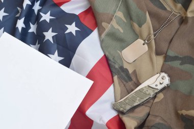 Ordu künyesi jetonu ve bıçağı eski kamuflaj üniformasının üzerinde duruyor ve Birleşik Devletler bayrağını katladı.