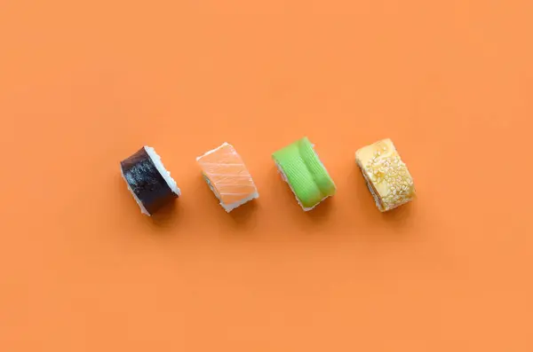 Различные типы азиатских суши рулоны на оранжевом фоне. Минимализм вид сверху квартира лежал с японской едой — стоковое фото