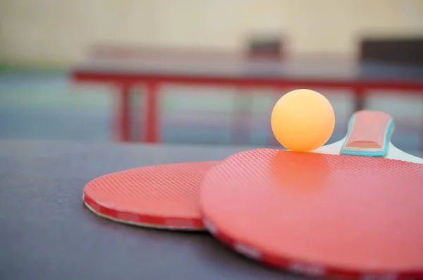 Schläger und Ball auf der Tischtennisplatte im Außensportplatz. Aktives Sport- und Bewegungskonzept — Stockfoto