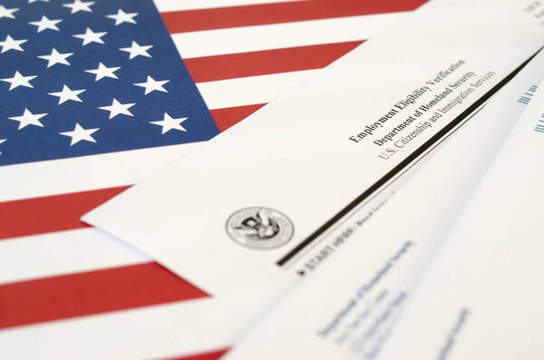 I-9 Employment Eligibility Verification blank form lies on United States flag with envelope from Department of Homeland Security