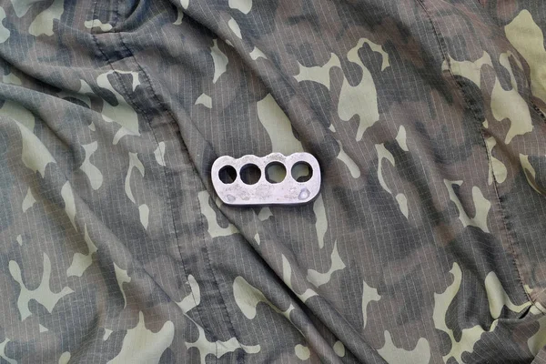 Iron brass cnuckles on crumpled camouflage clothes close up. Football hooliganism and racism concept — 스톡 사진