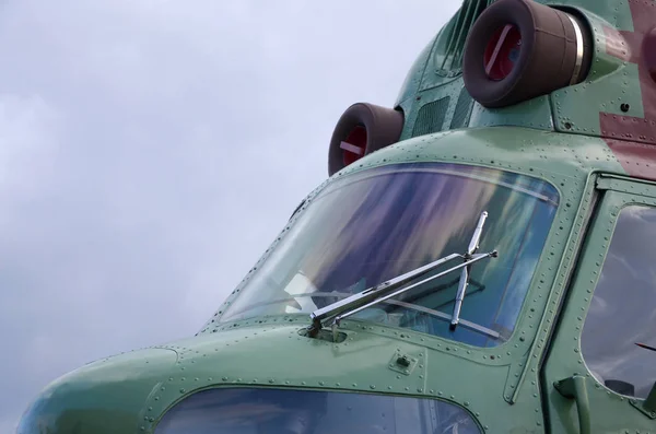 Helicopter cabin fragment close up. Camouflage aircraft fuselage and bulletproof glass