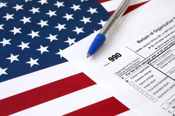 Форма 990 Повернення організації звільняється від податку на прибуток і синьої ручки на прапорі США. Податкова форма внутрішнього доходу. — стокове фото