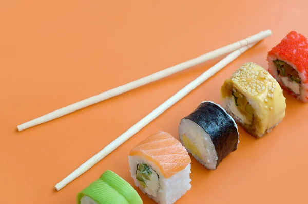 Olika typer av asiatiska sushi rullar på orange bakgrund. Minimalism ovanifrån platt låg med japansk mat — Stockfoto